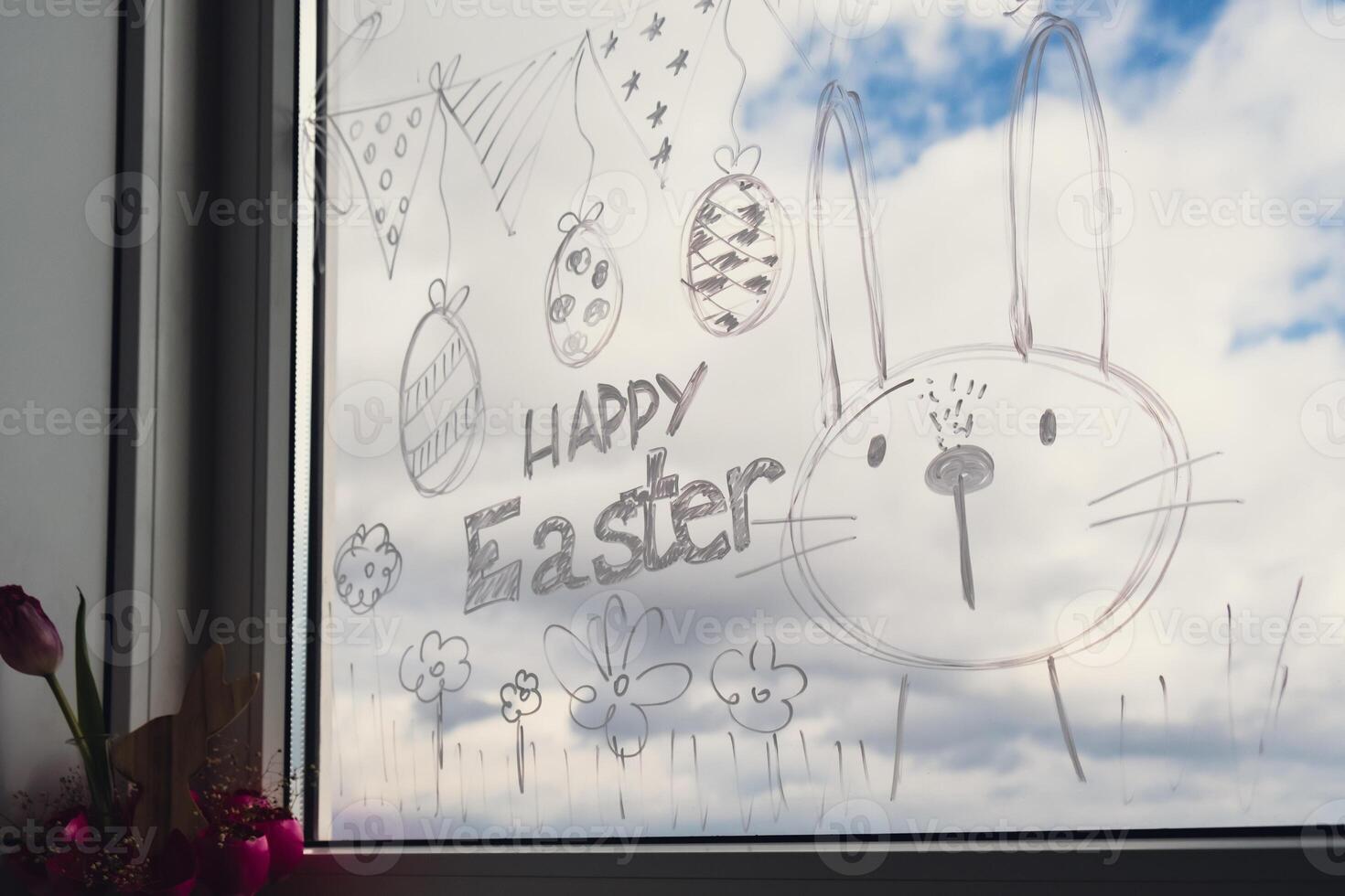 HAPPY EASTER text on creative painted window with white marker. Easter bunny rabbit decoration on big clear window. Springtime idea home decoration. Holiday preparation photo