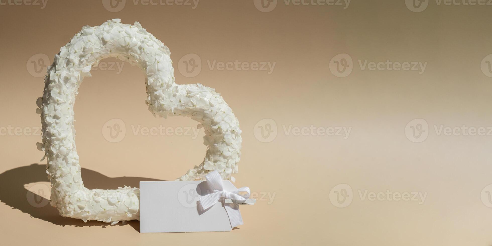Empty paper note mock up White lilac flowers heart shaped in pastel backdrop. Symbol of love floral arrangement. Spring concept idea Valentine's Day, weeding proposal postcard copy space for your text photo