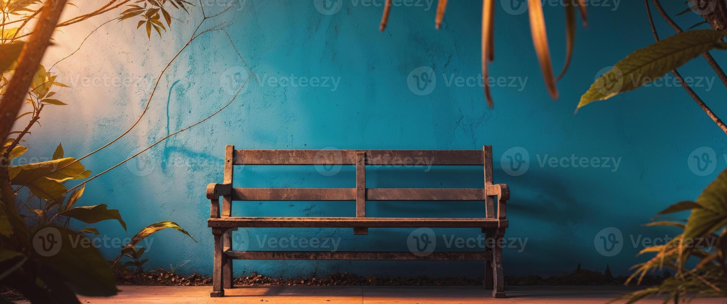 An empty wooden bench in front of a blue wall photo
