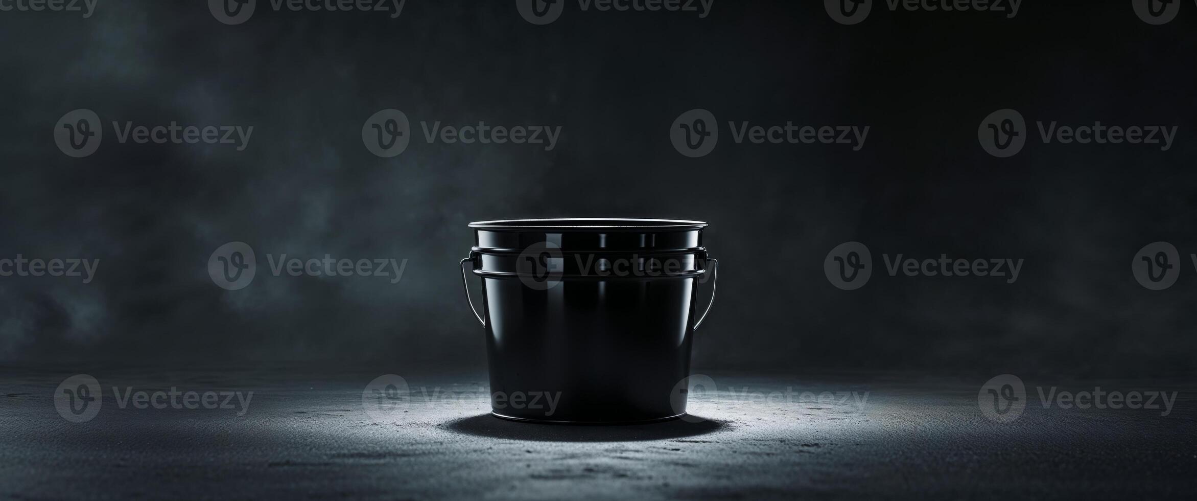 Black bucket on a dark surface with dramatic lighting effects. photo