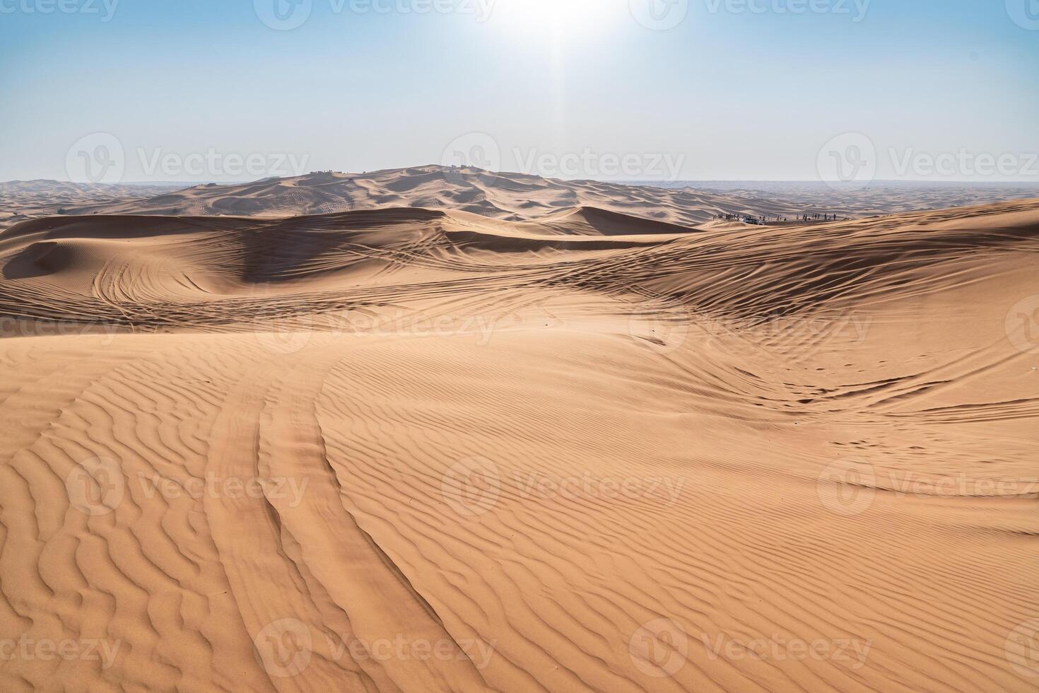 tire marks of off-road vehicles and human footprints on desert dunes near Dubai during a sunny day photo