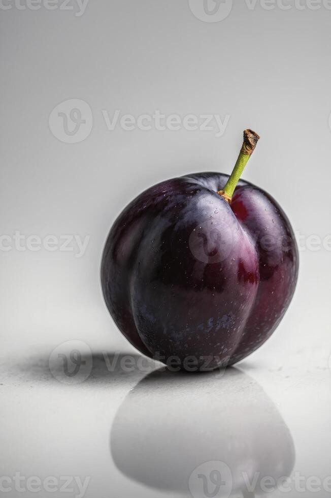 Close-up of Ripe Plum with Stem and Reflection on White Surface photo