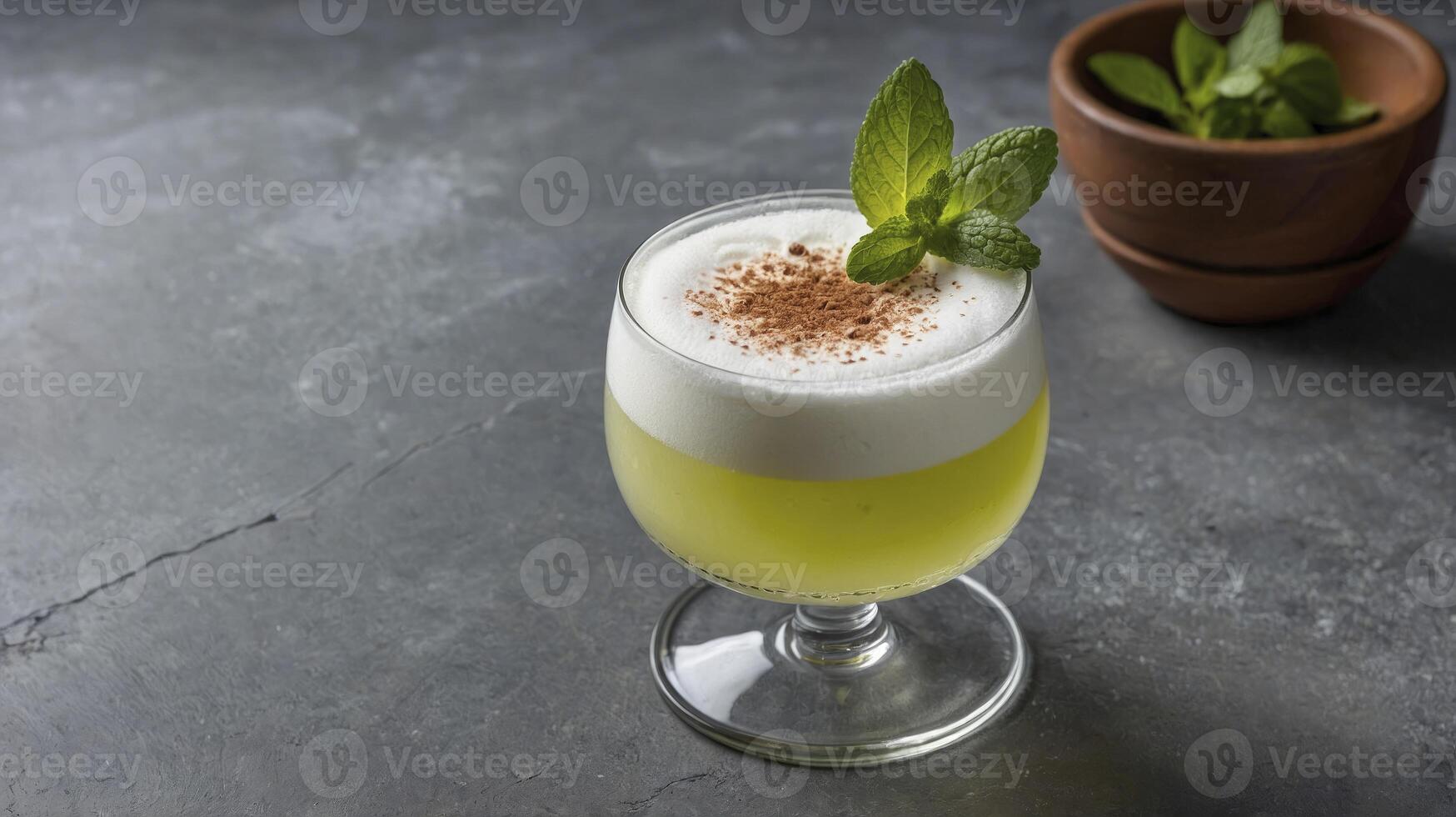 Refreshing Pisco Sour Cocktail in Glass with Mint Sprig on Grey Surface photo