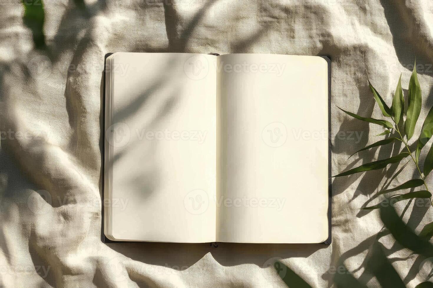 Open Blank Notebook with Leaves Shadow on Fabric Background Still Life photo