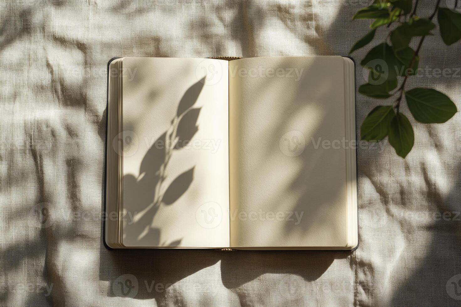 Open Notebook with Sunlight and Leaf Shadows on Linen Surface photo