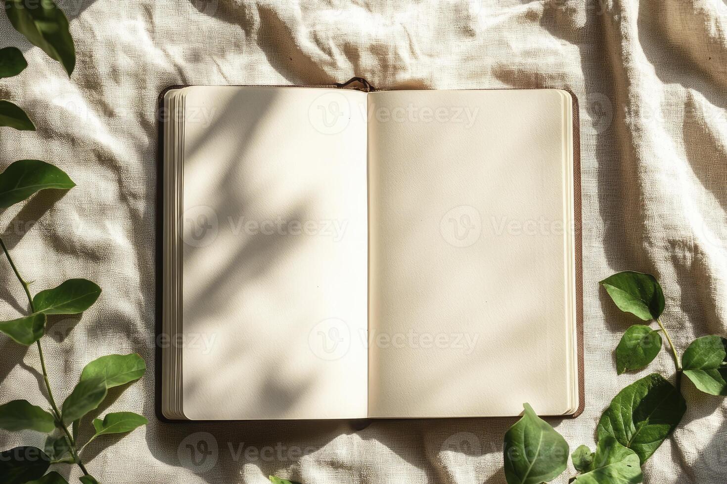 Open Notebook Mockup with Blank Pages and Natural Green Leaves photo