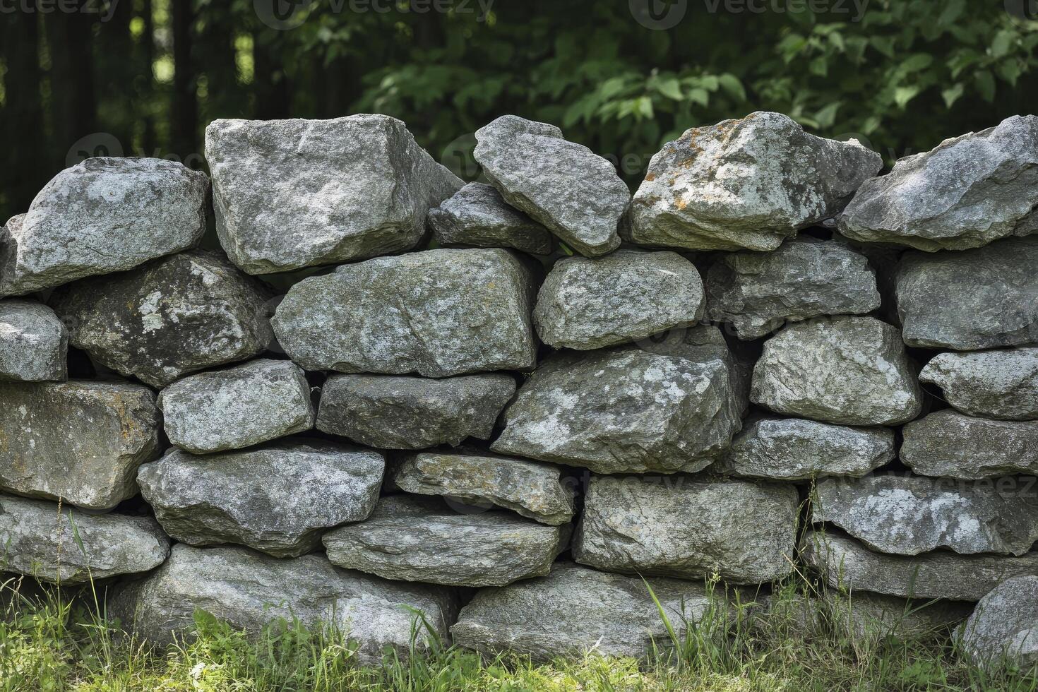 Stone Wall Constructed From Gray Rocks with Lush Green Background photo