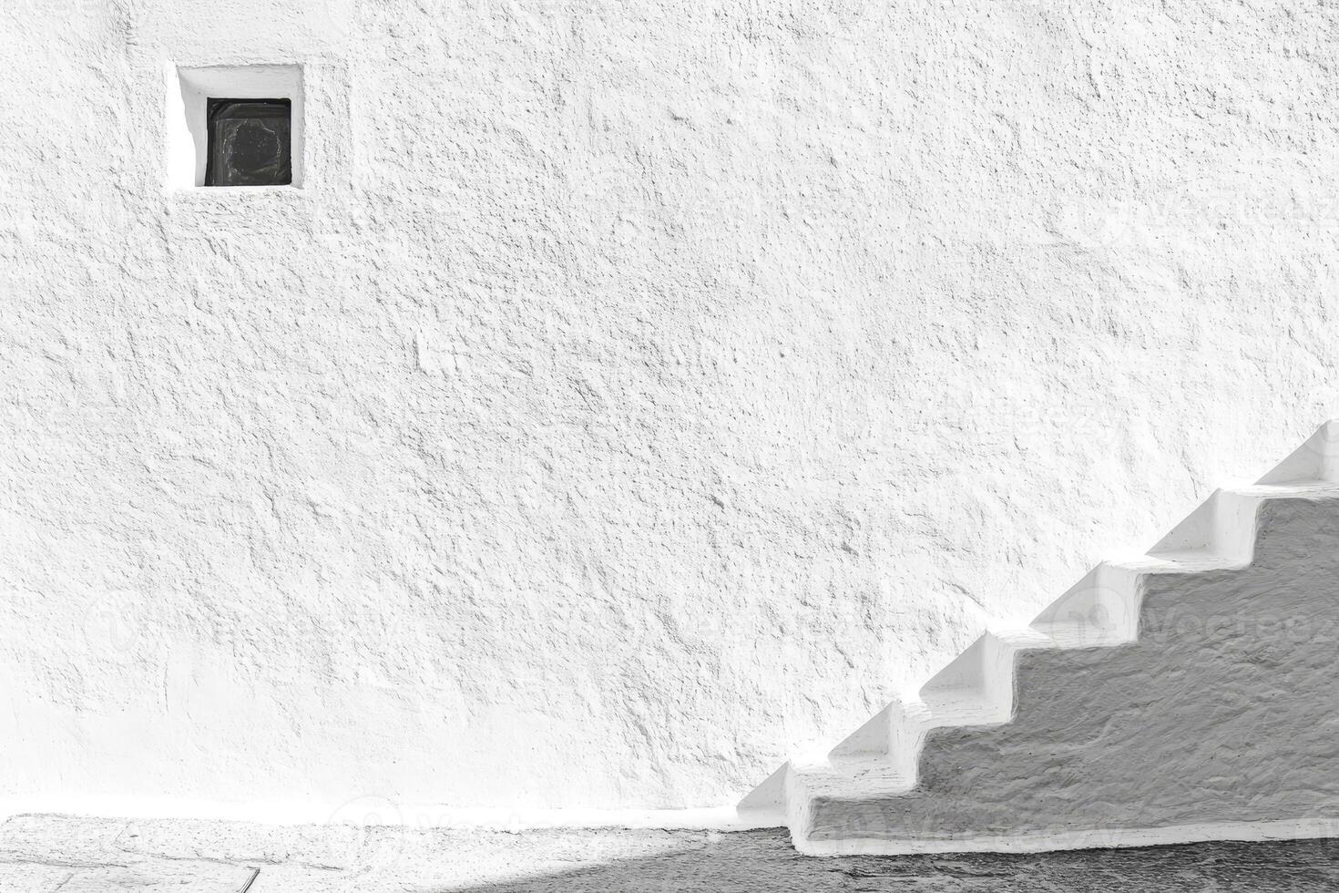 White Wall with Small Window and Steps Leading Upward in Sunlight photo