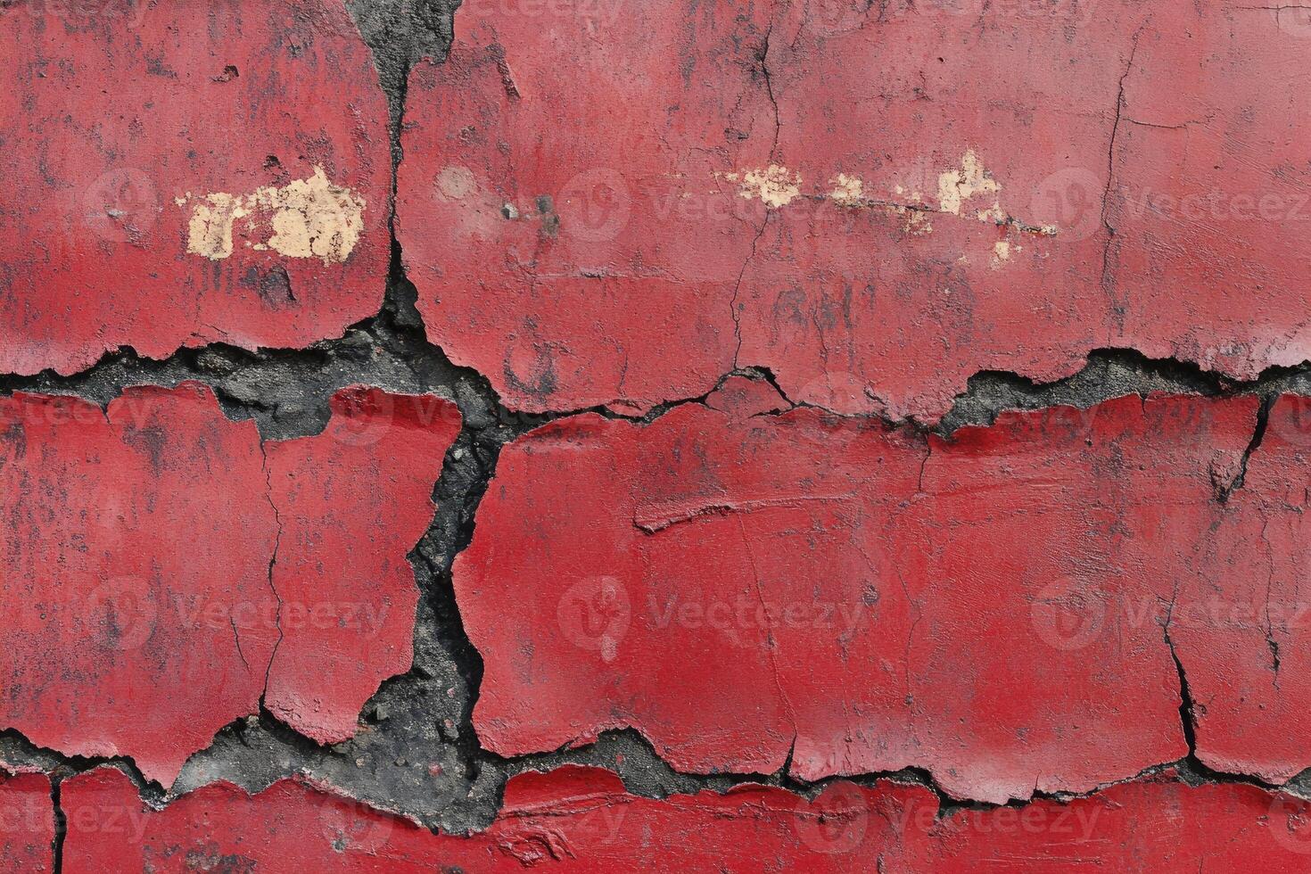 Cracked Red Painted Surface with Underlying Concrete Showing Detail photo