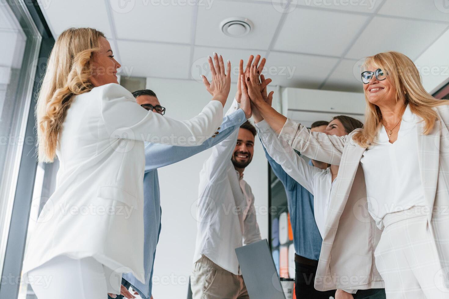 Doing high five... Successful agreement. Group of professional business people is in the office photo