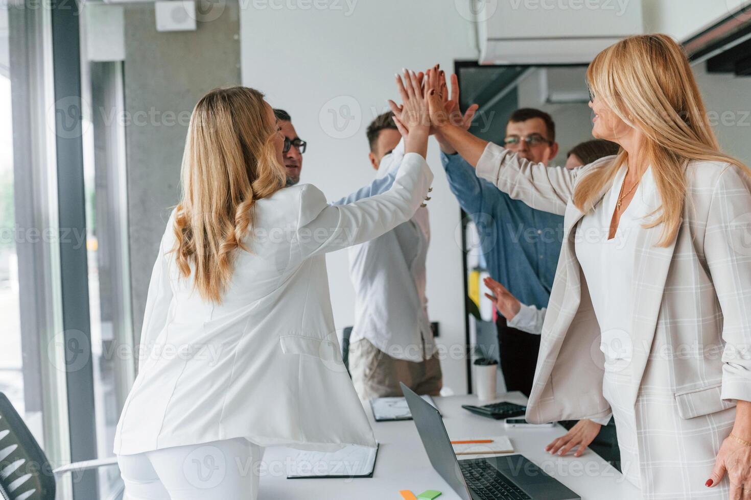 Doing high five. Successful agreement. Group of professional business people is in the office photo
