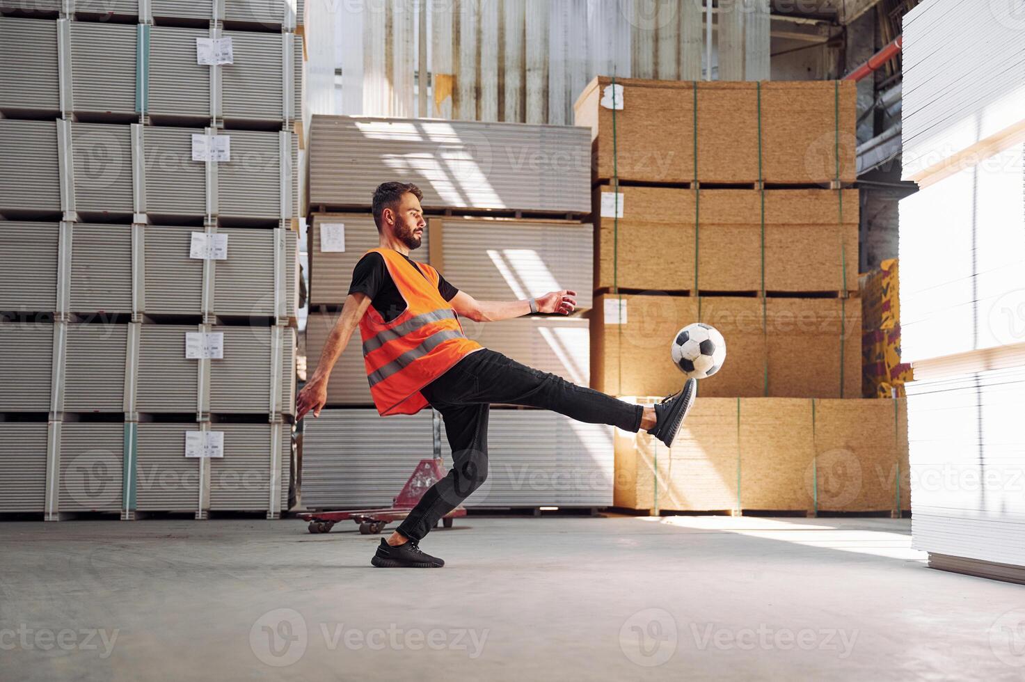 Kicking a soccer ball on the break time. Storage worker is in the warehouse with bunch of products photo