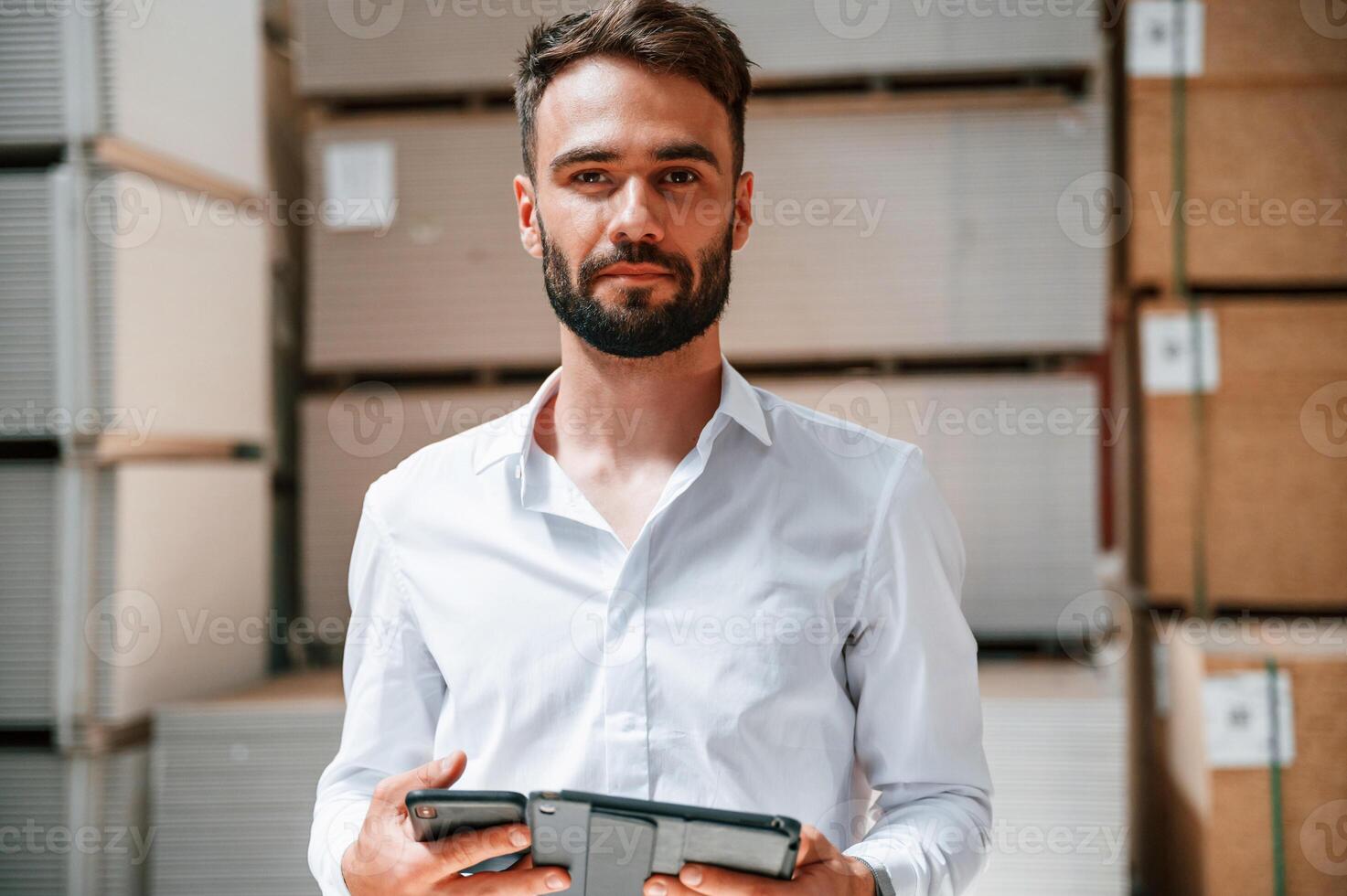 Storage worker is in the warehouse with bunch of products photo