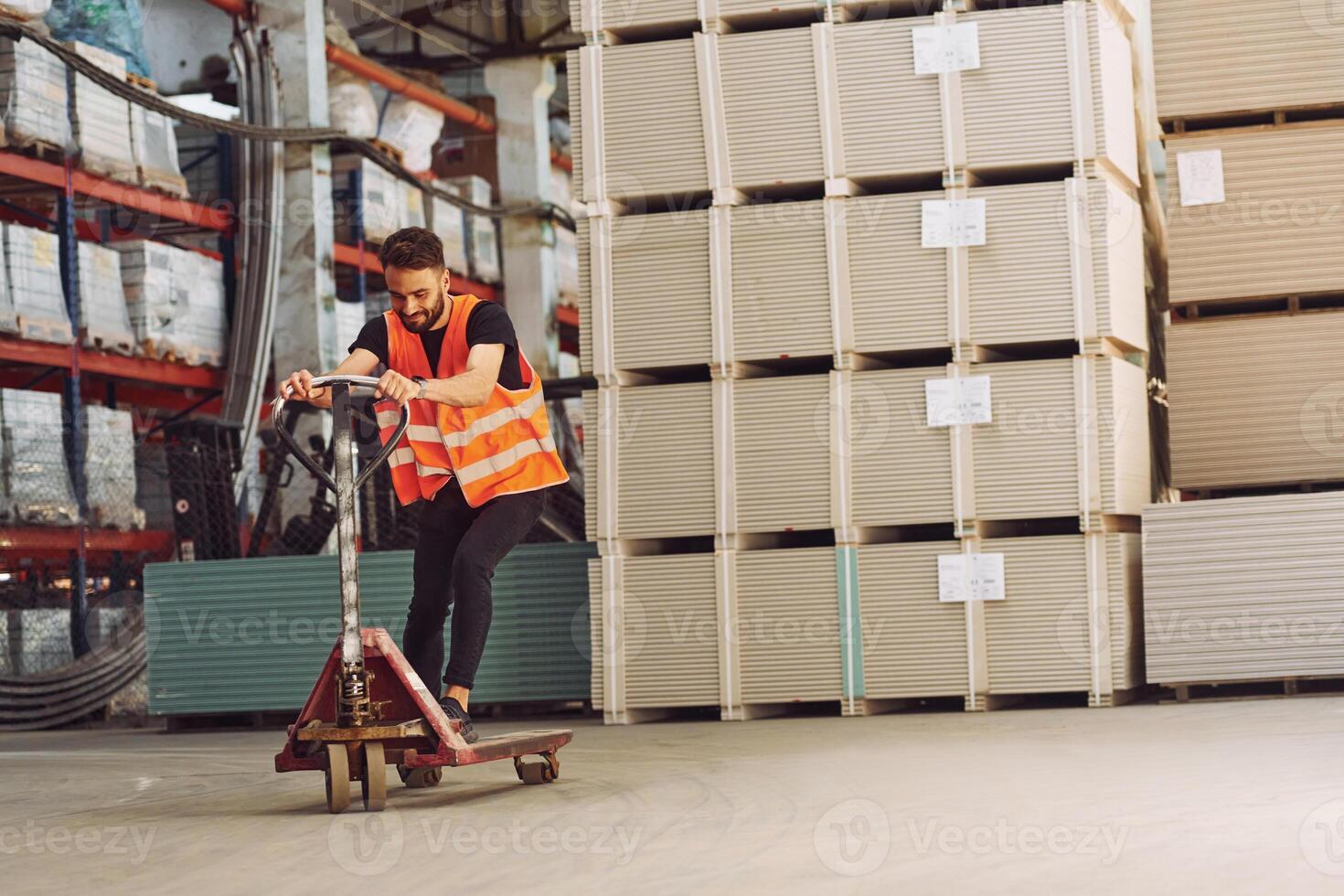 Riding, the platform trolley.. Storage worker is in the warehouse with bunch of products photo