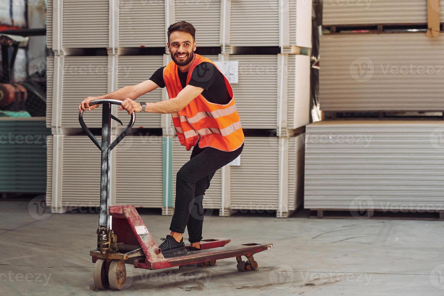 Riding ,the platform trolley. Storage worker is in the warehouse with bunch of products photo
