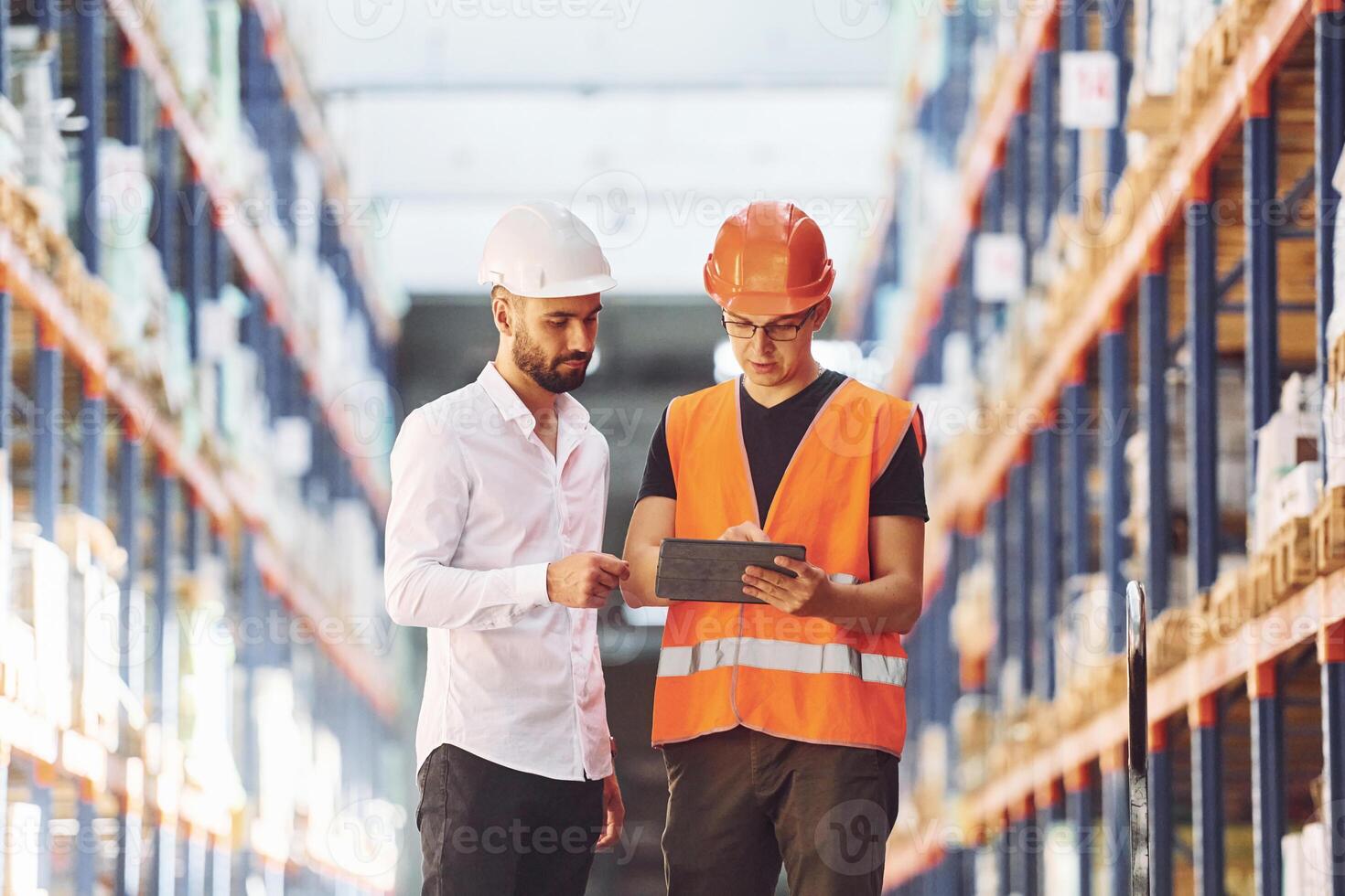 Talking to each other. T,wo storage workers is in the warehouse photo