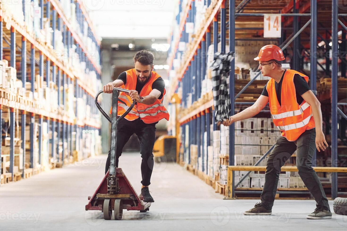 Man riding trolley platform,. Having fun. Two storage workers is in the warehouse photo