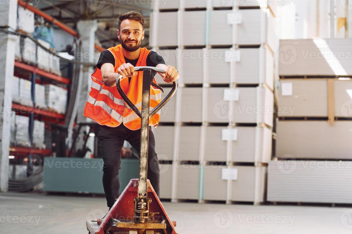 Riding the platform trolley.. Storage worker is in the warehouse with bunch of products photo