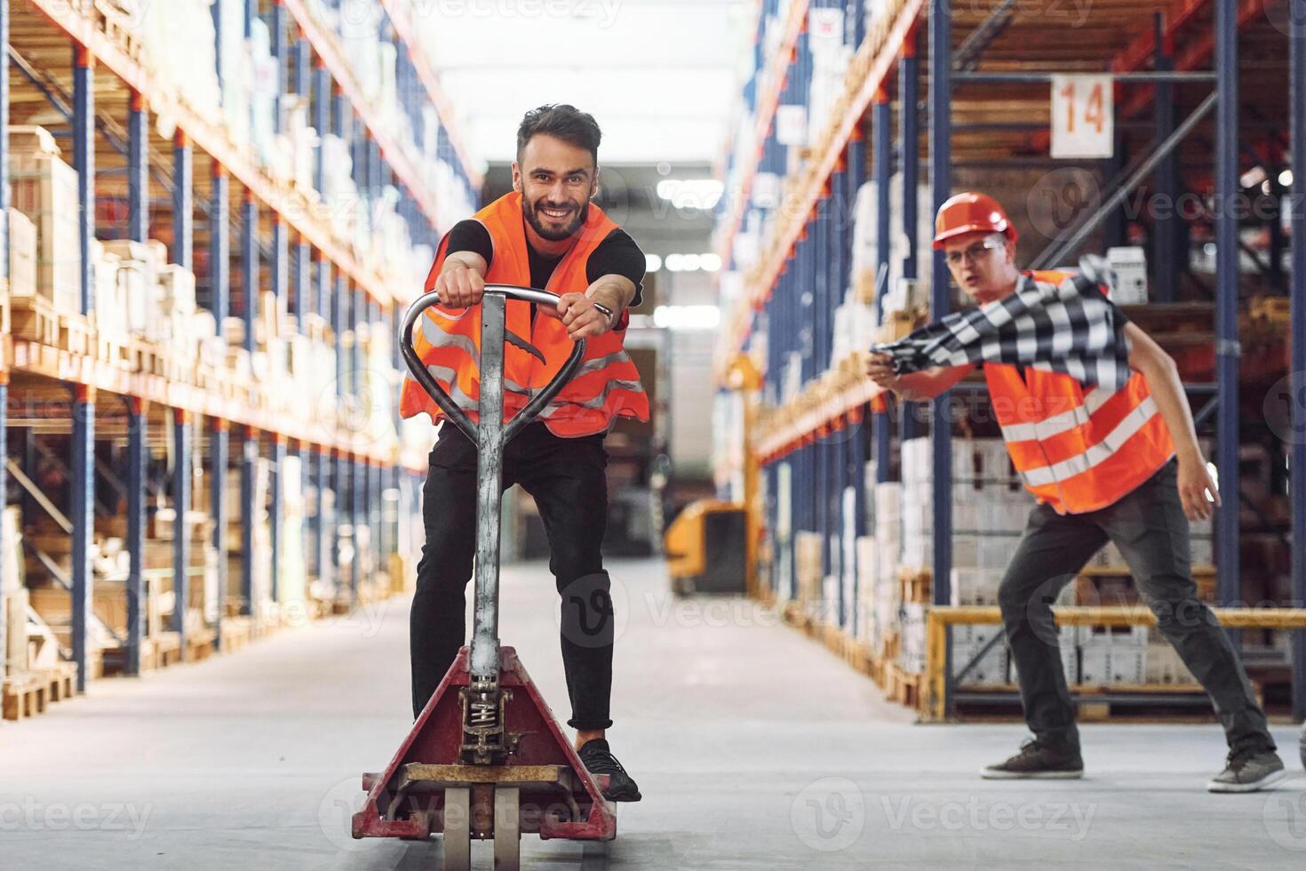 Man riding trolley platform. ,Having fun. Two storage workers is in the warehouse photo
