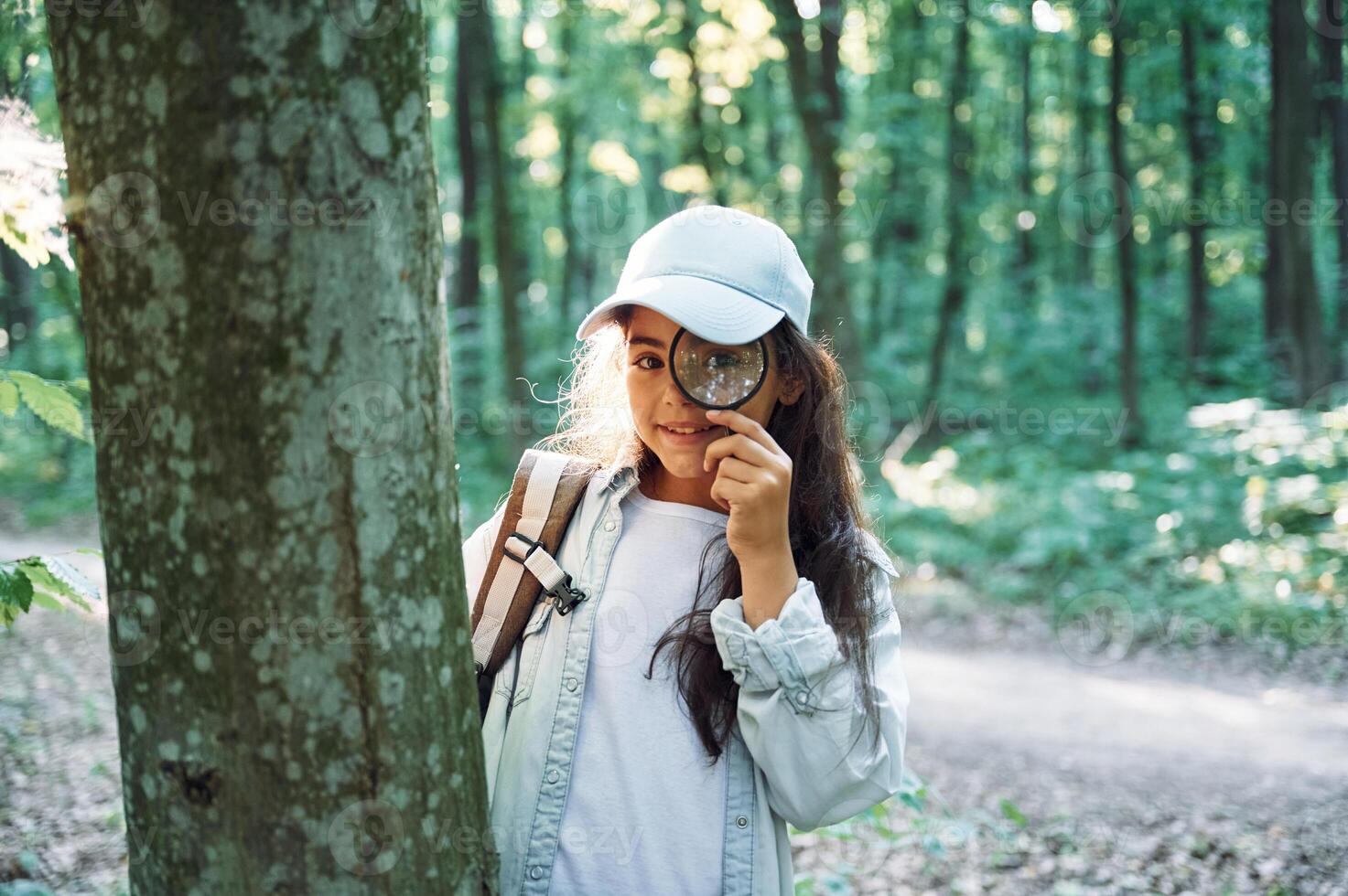 Using magnifying glass., Girl is in the forest at summer day time discovering new places photo
