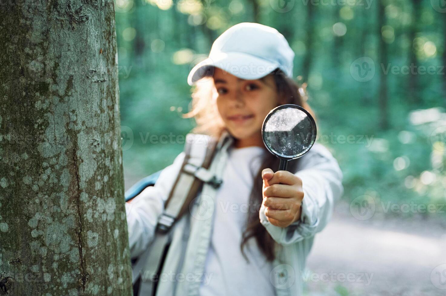 Using magnifying glass. ,Girl is in the forest at summer day time discovering new places photo