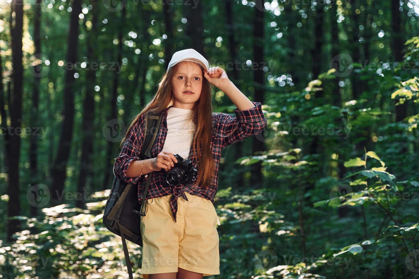 Young photographer with camera.. Girl is in the forest at summer day time discovering new places photo