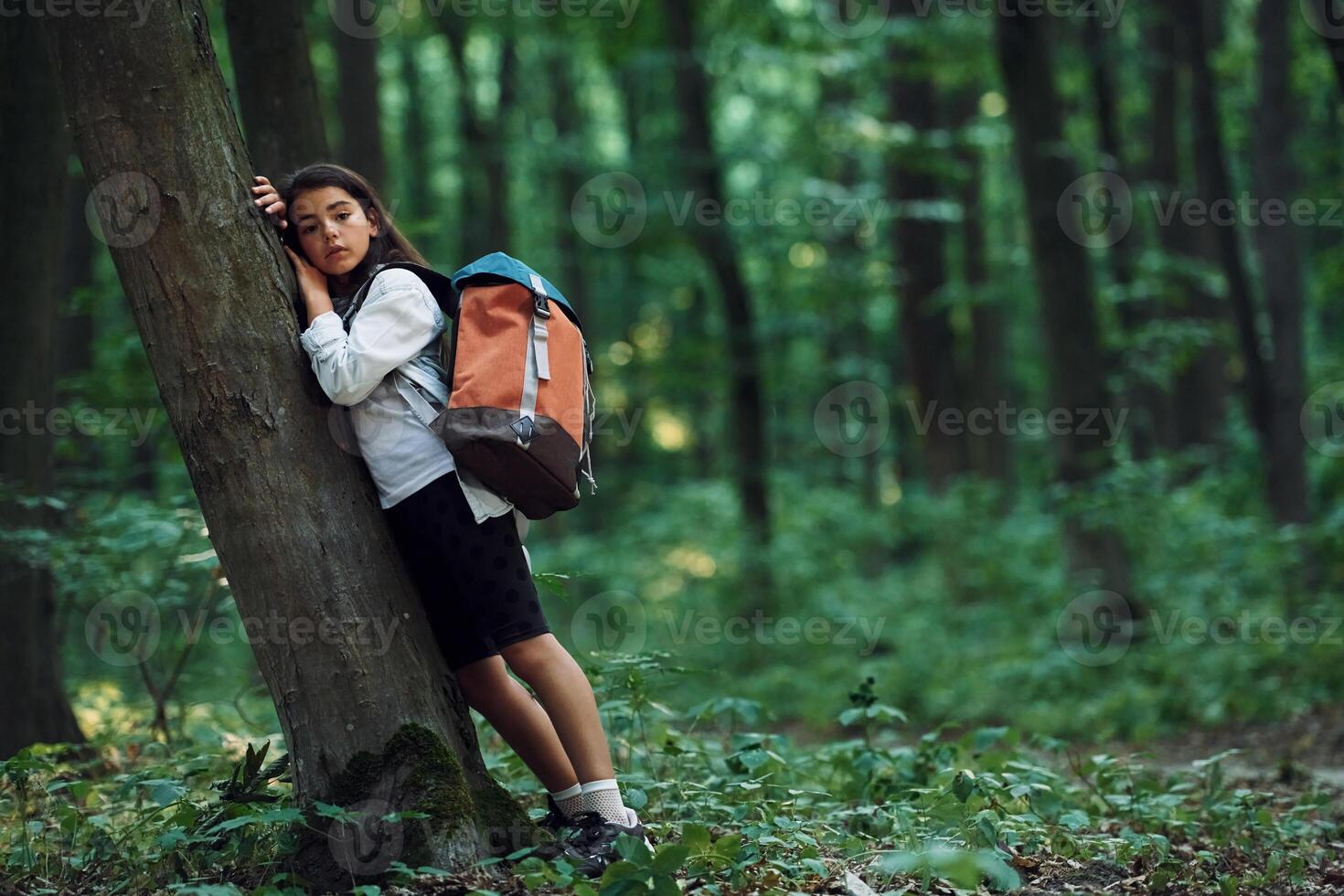 Leaning on the tree... Girl is in the forest at summer day time discovering new places photo