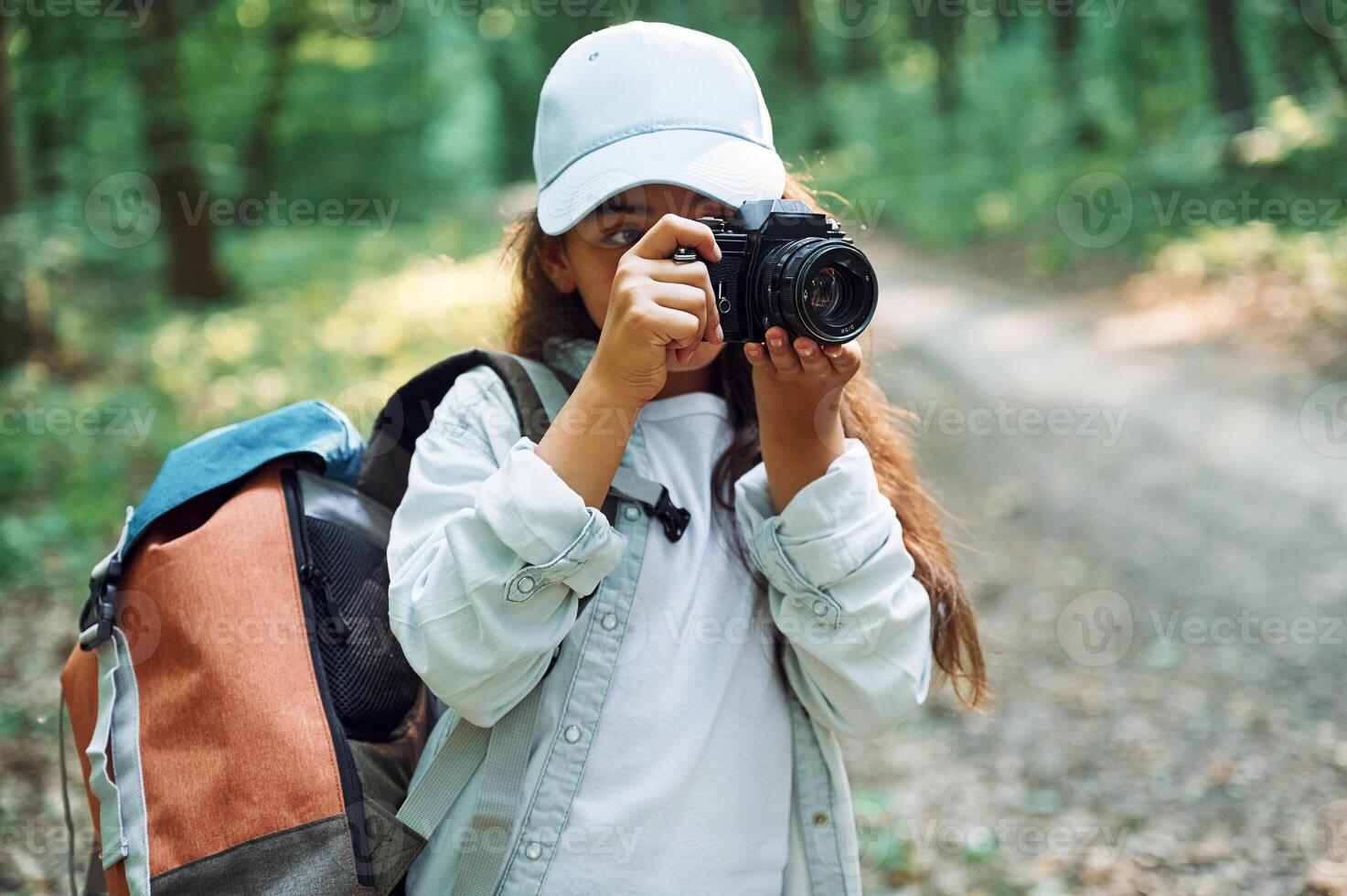 Using professional camera.. Girl is in the forest at summer day time discovering new places photo