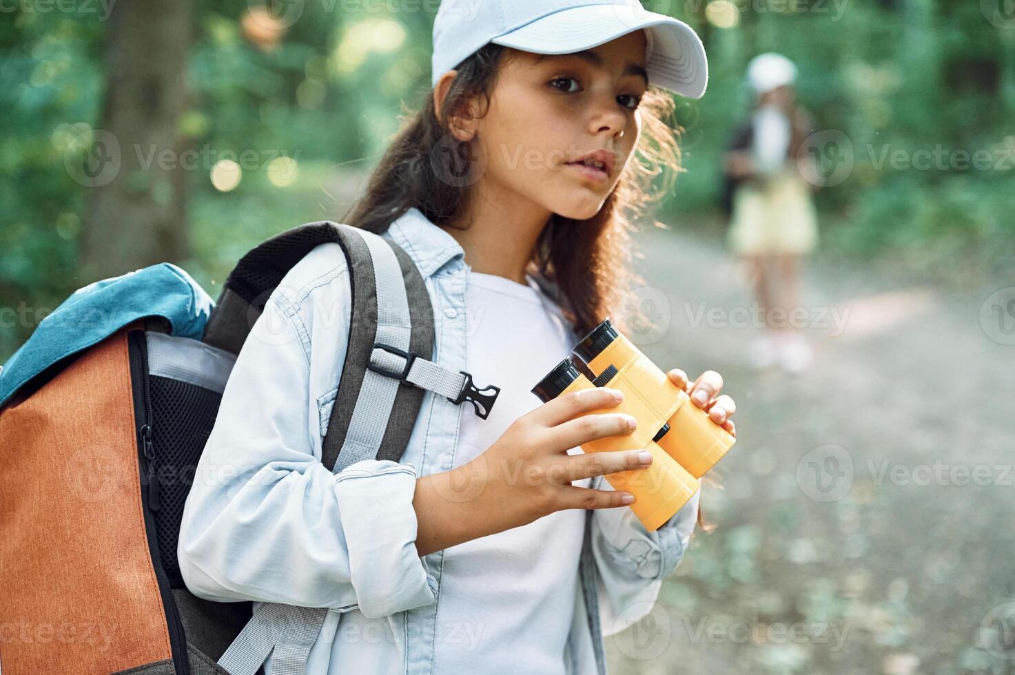 Holding orange colored binoculars.. Two girls is in the forest having a leisure activity, discovering new places photo