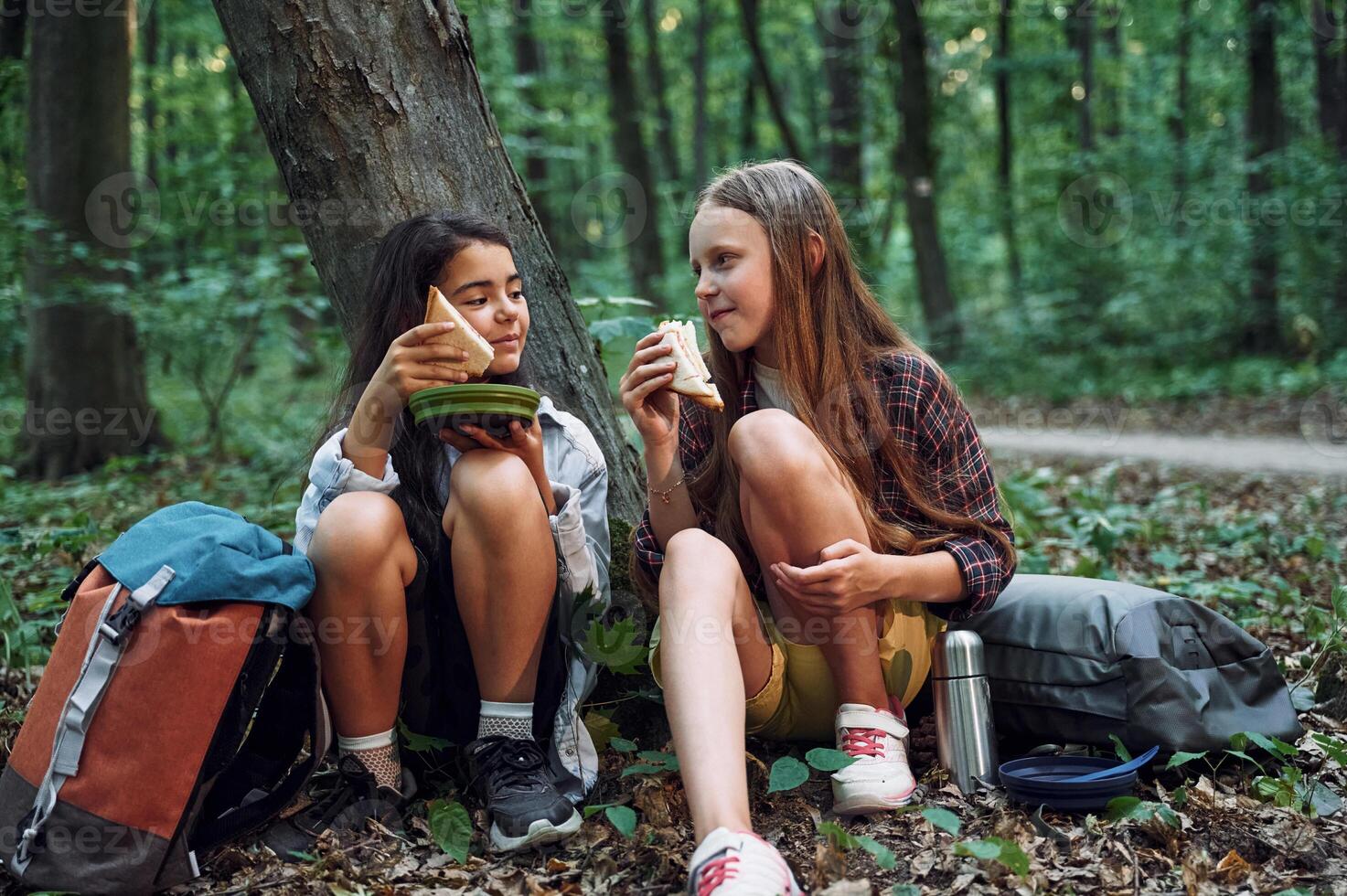 Sitting and eating.. Two girls is in the forest, having a leisure activity, discovering new places photo