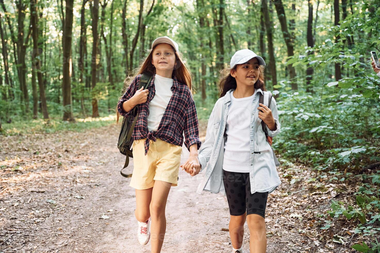 Walking forward. .Two girls is in the forest having a leisure activity, discovering new places photo