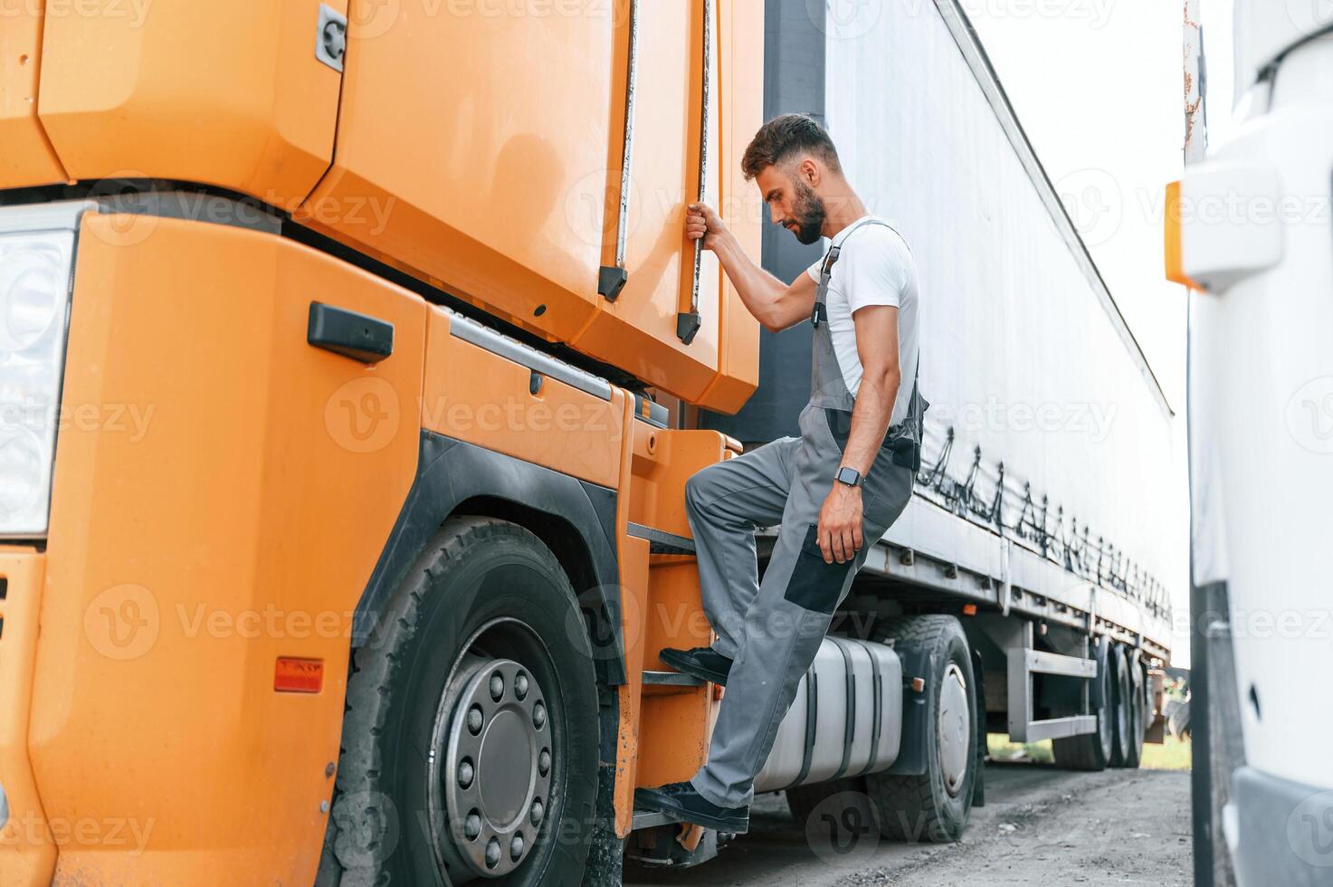 Climbing, to the vehicle by holding the door. Man in unifrom doing service for big truck vehicle photo