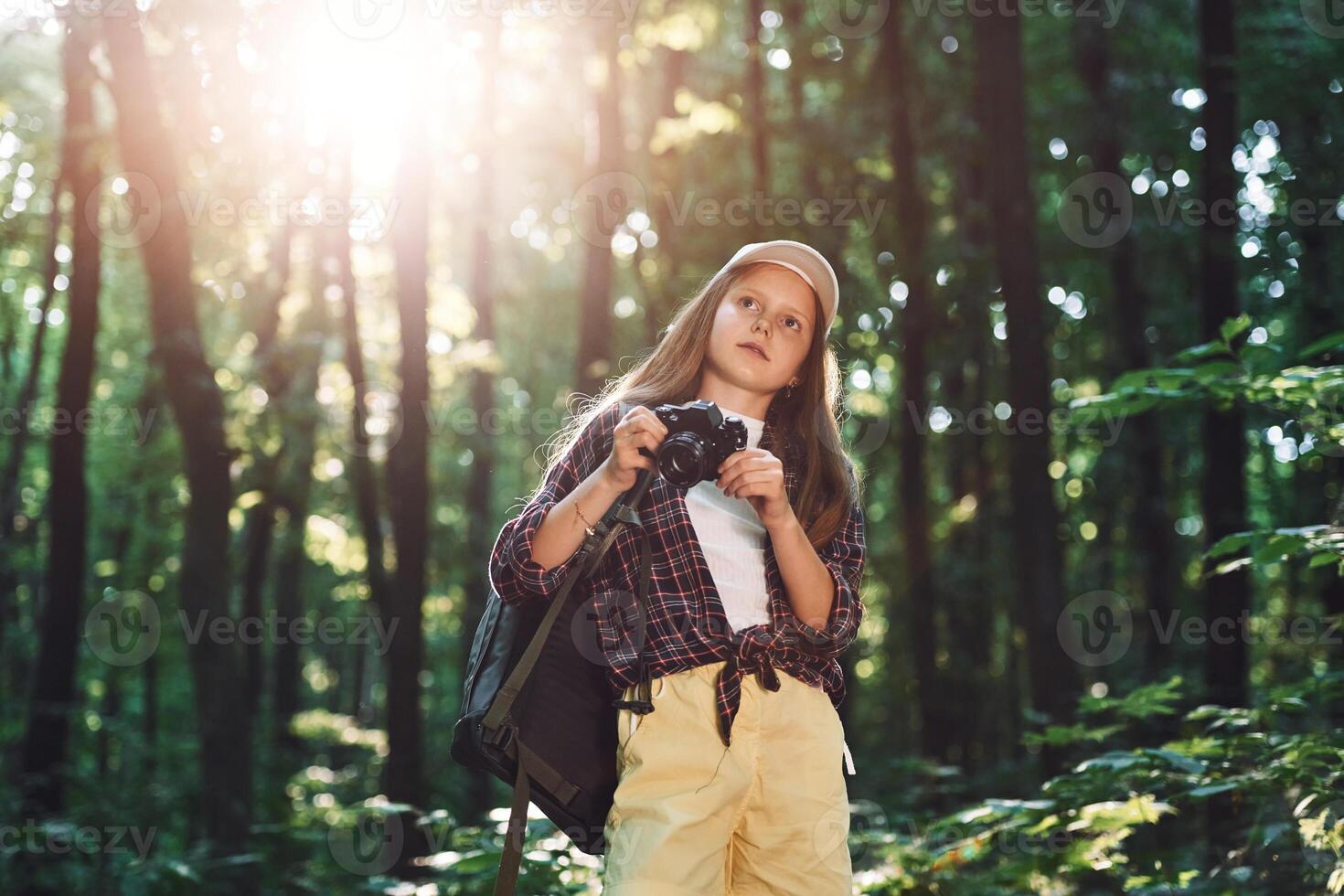 Young photographer with camera. Girl, is in the forest at summer day time discovering new places photo