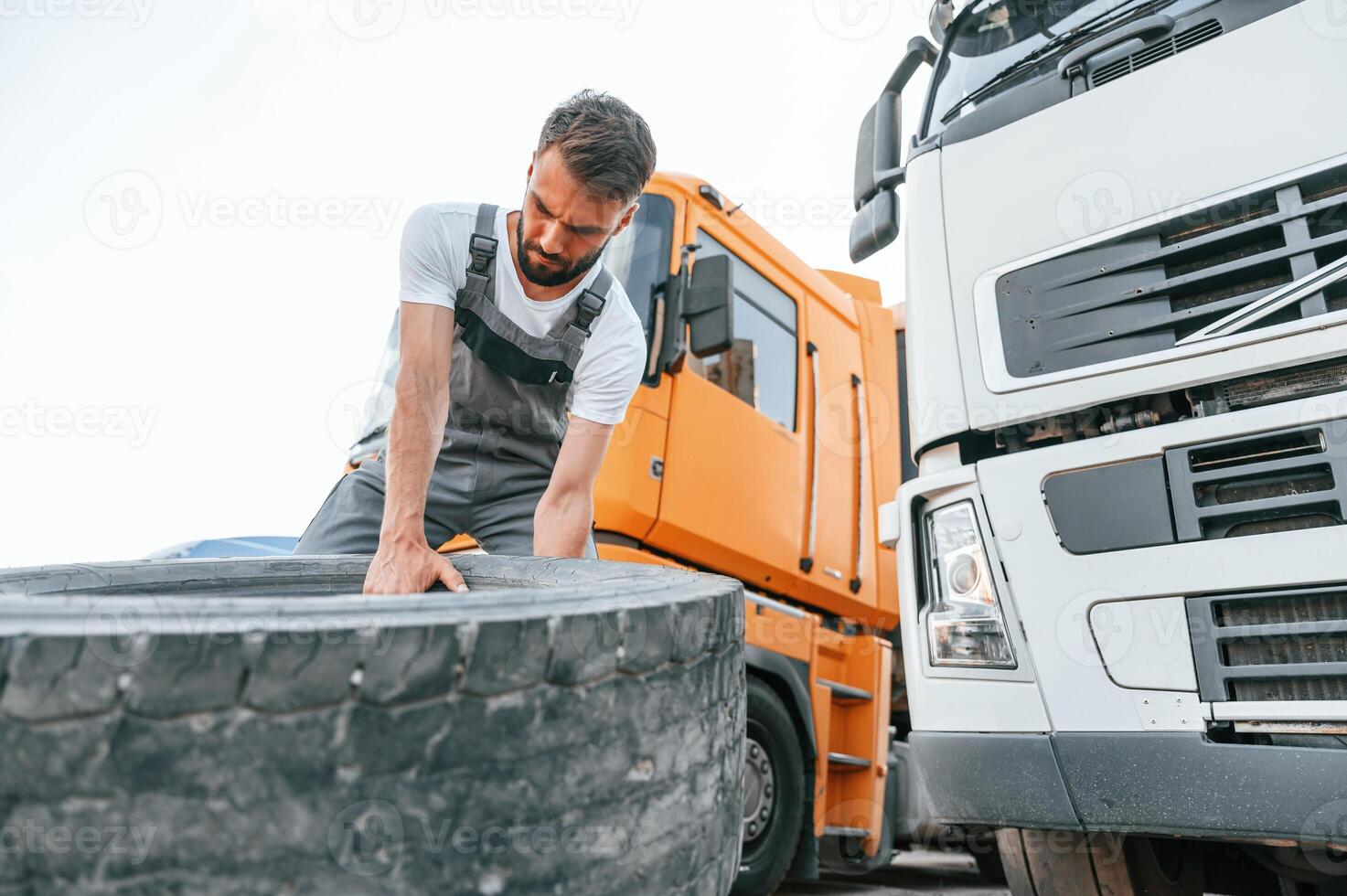Moving broken tire. Man ,in unifrom doing service for big truck vehicle photo