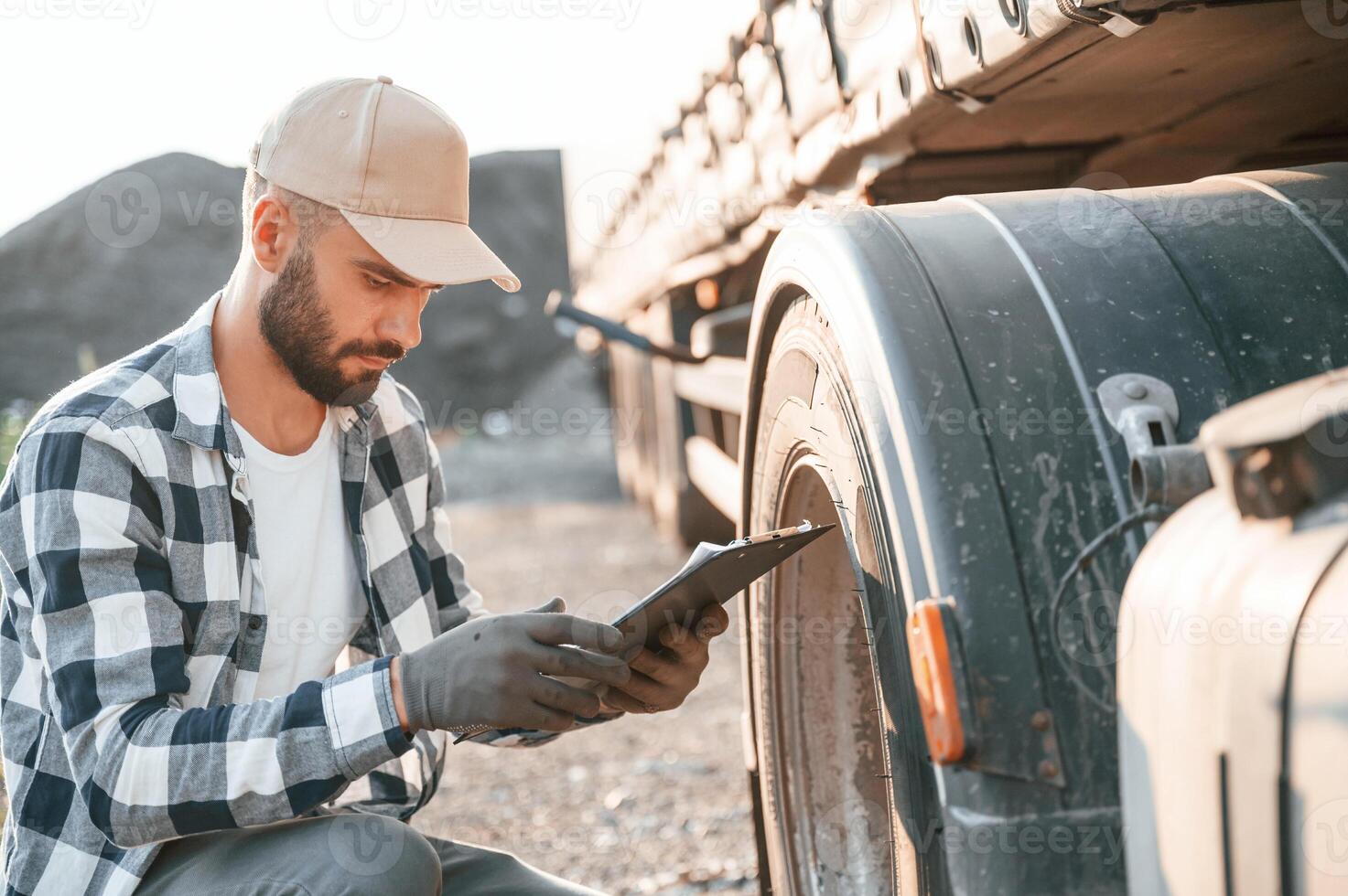 Testing the tires.. Young truck driver is with his vehicle at daytime photo