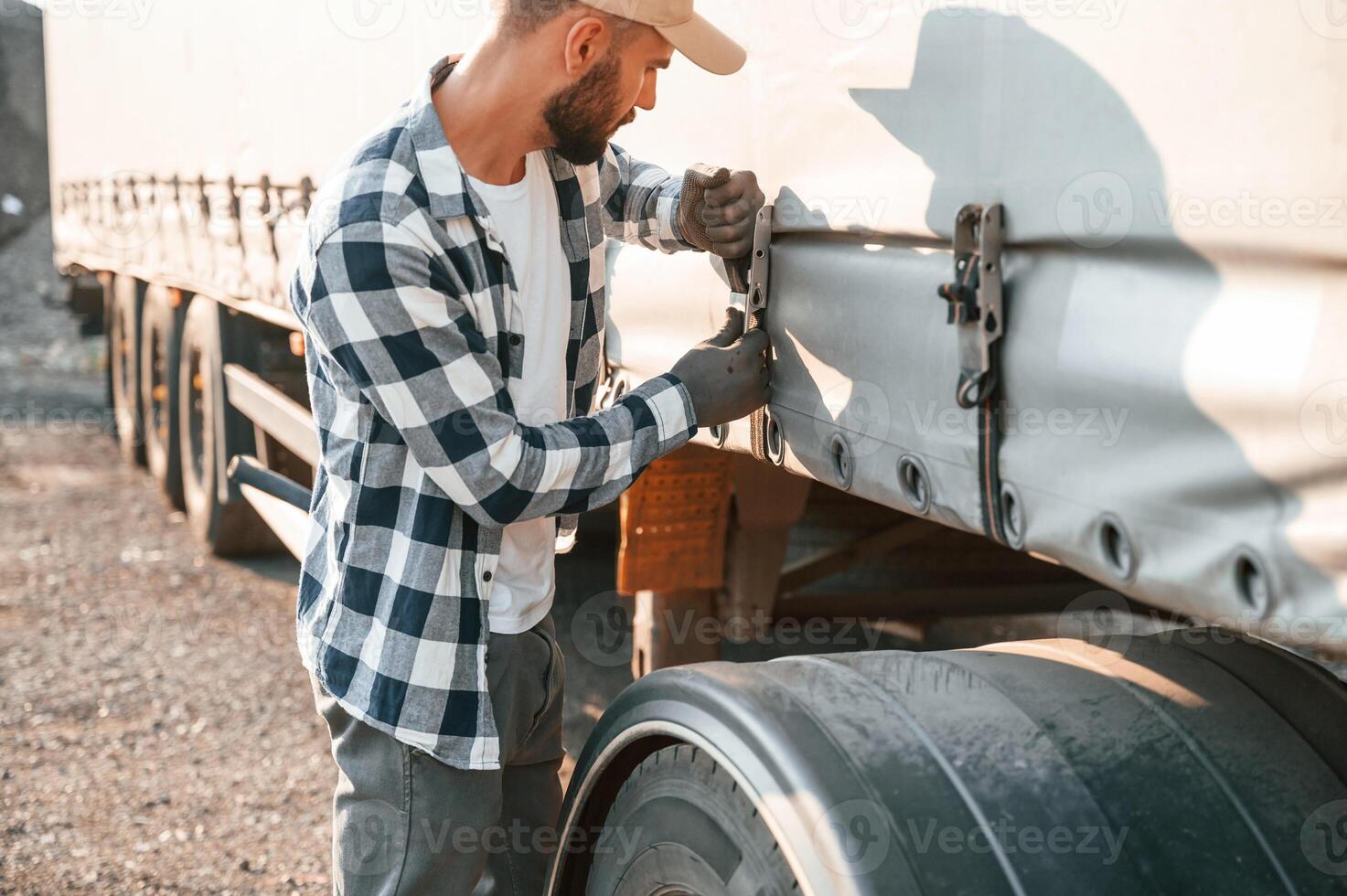 Checking the ropes.. Young, truck driver is with his vehicle at daytime photo