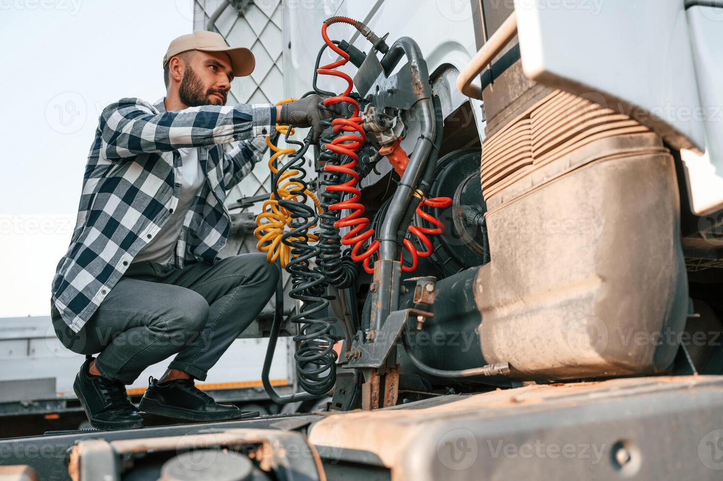 Checking the wires connection.. Young truck driver ,is with his vehicle at daytime photo