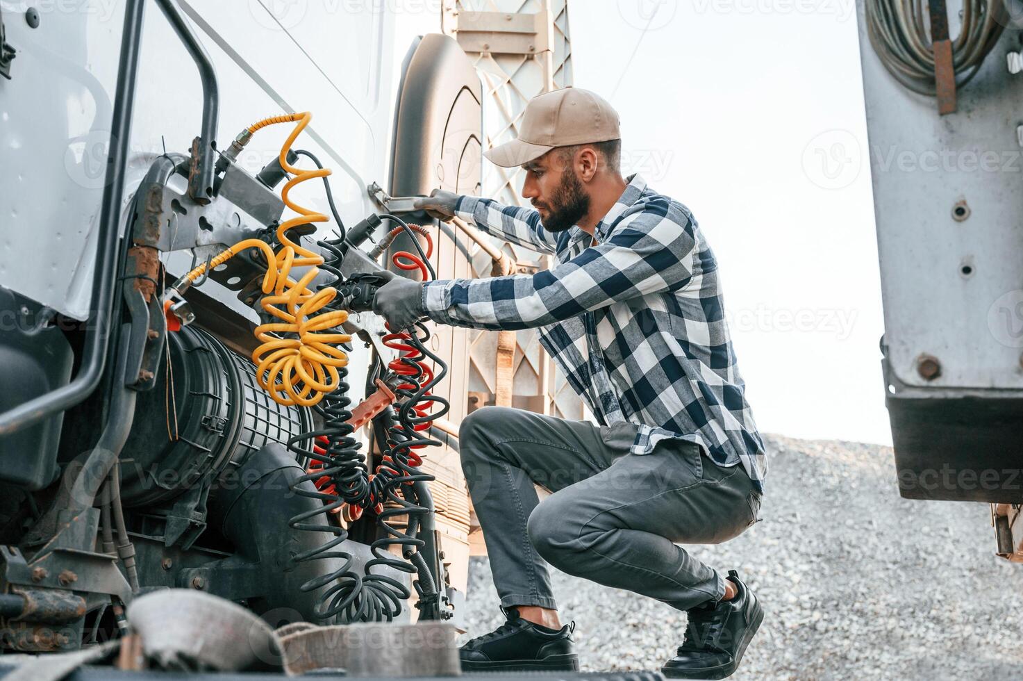 Checking, the wires connection. Young truck driver is with his vehicle at daytime photo