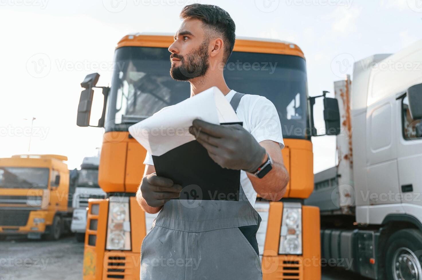 Holding notepad. Quality control. Man in unifrom doing service for big truck vehicle. photo