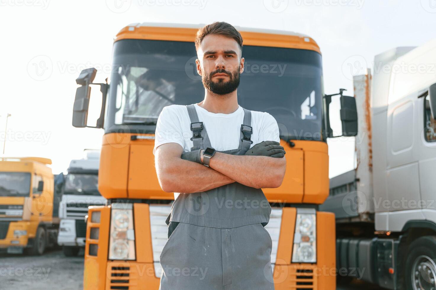 Standing, and posing for the camera. .Man in unifrom doing service for big truck vehicle photo