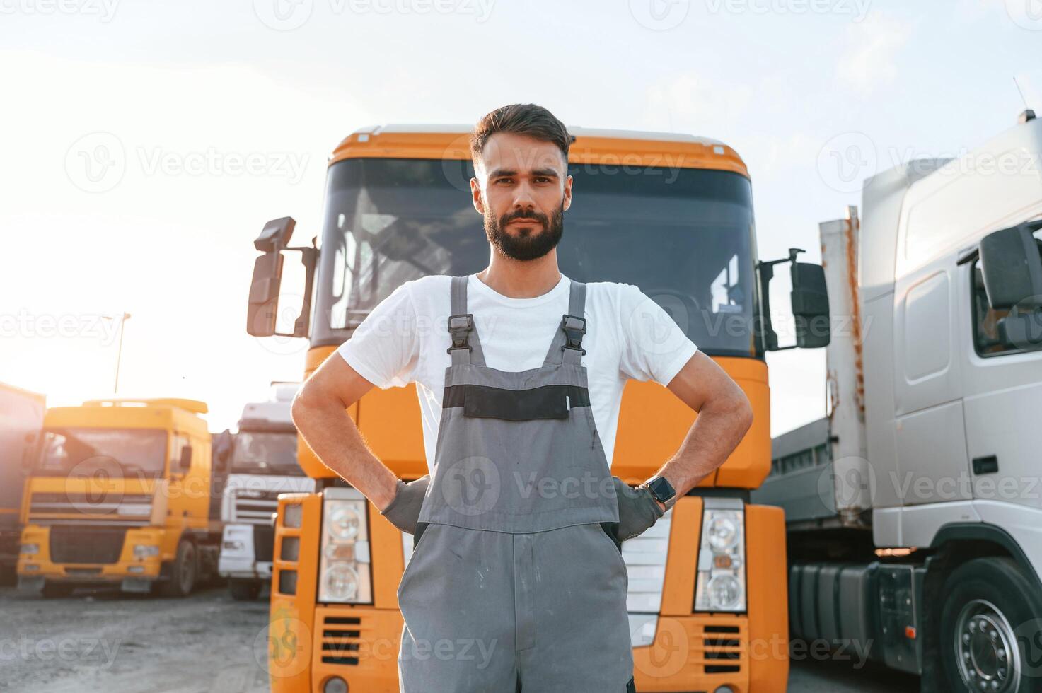 Standing and posing for the camera. Man in unifrom doing service for big truck vehicle. photo