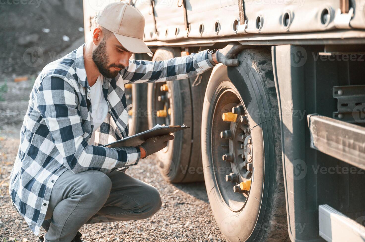 Working with wheels. Young truck driver is with his vehicle at daytime photo