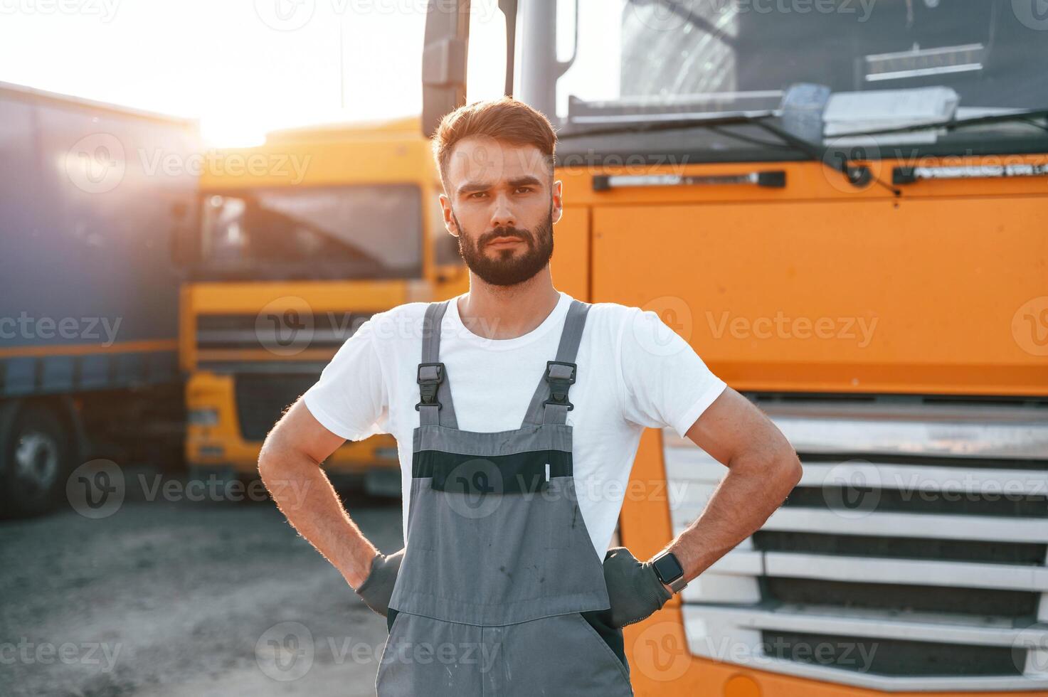 Standing and posing for the camera. Man in unifrom doing service for big truck vehicle photo
