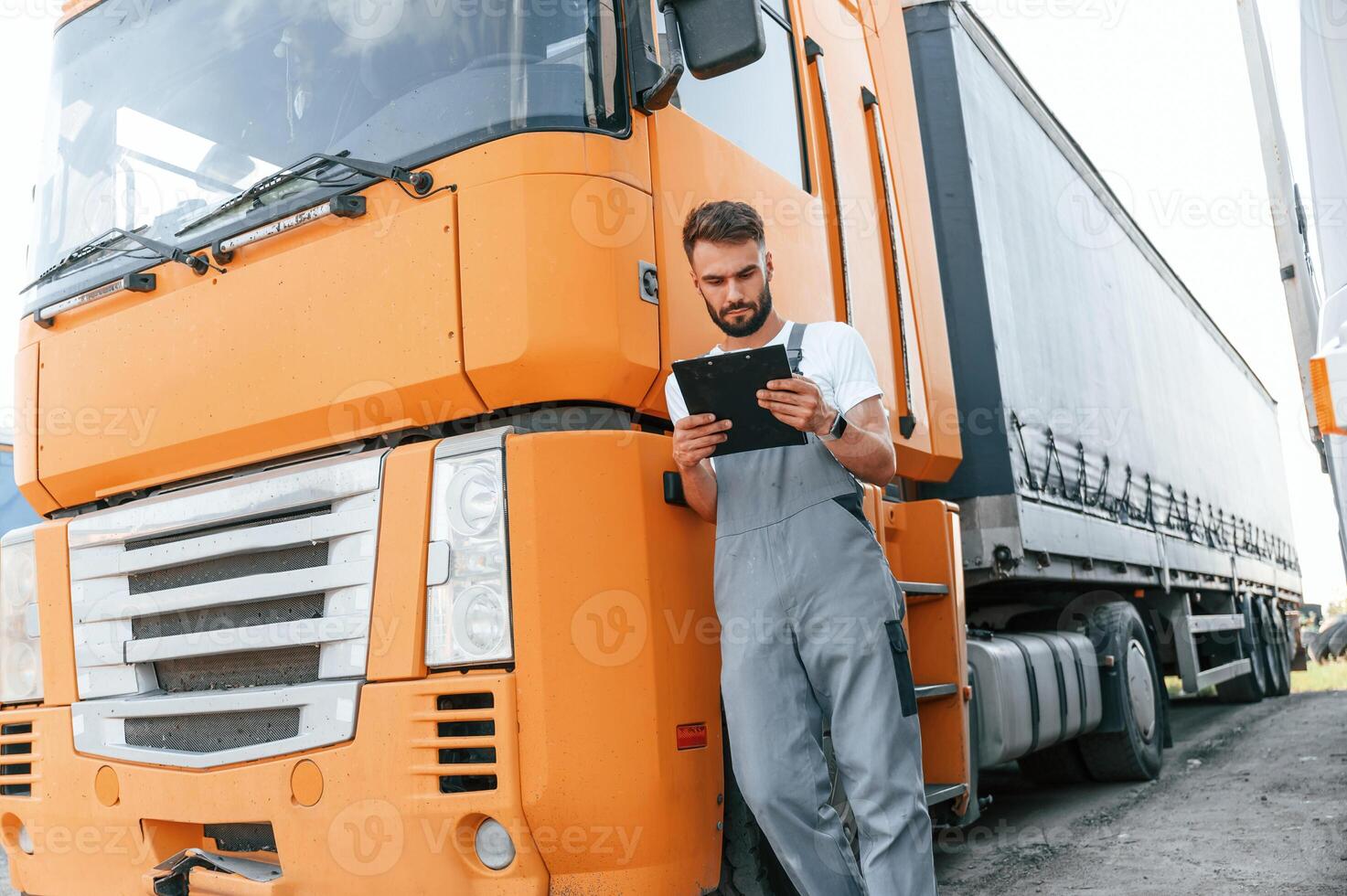 Holding notepad. Man in unifrom doing service for big truck vehicle photo