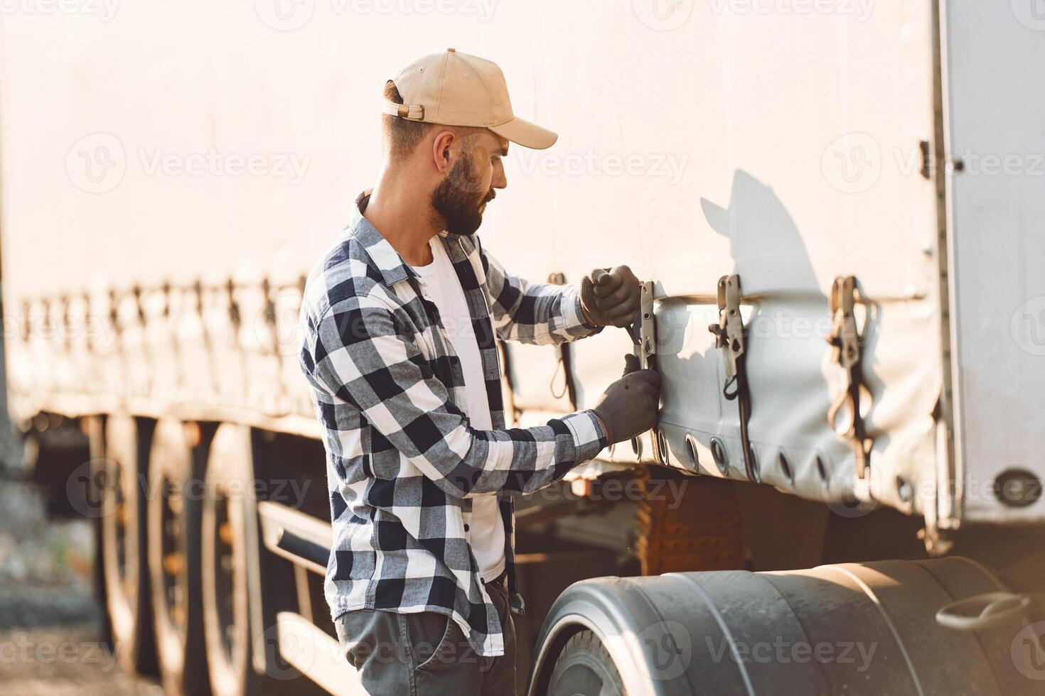 Ready for the ride. Young truck driver is with his vehicle at daytime photo