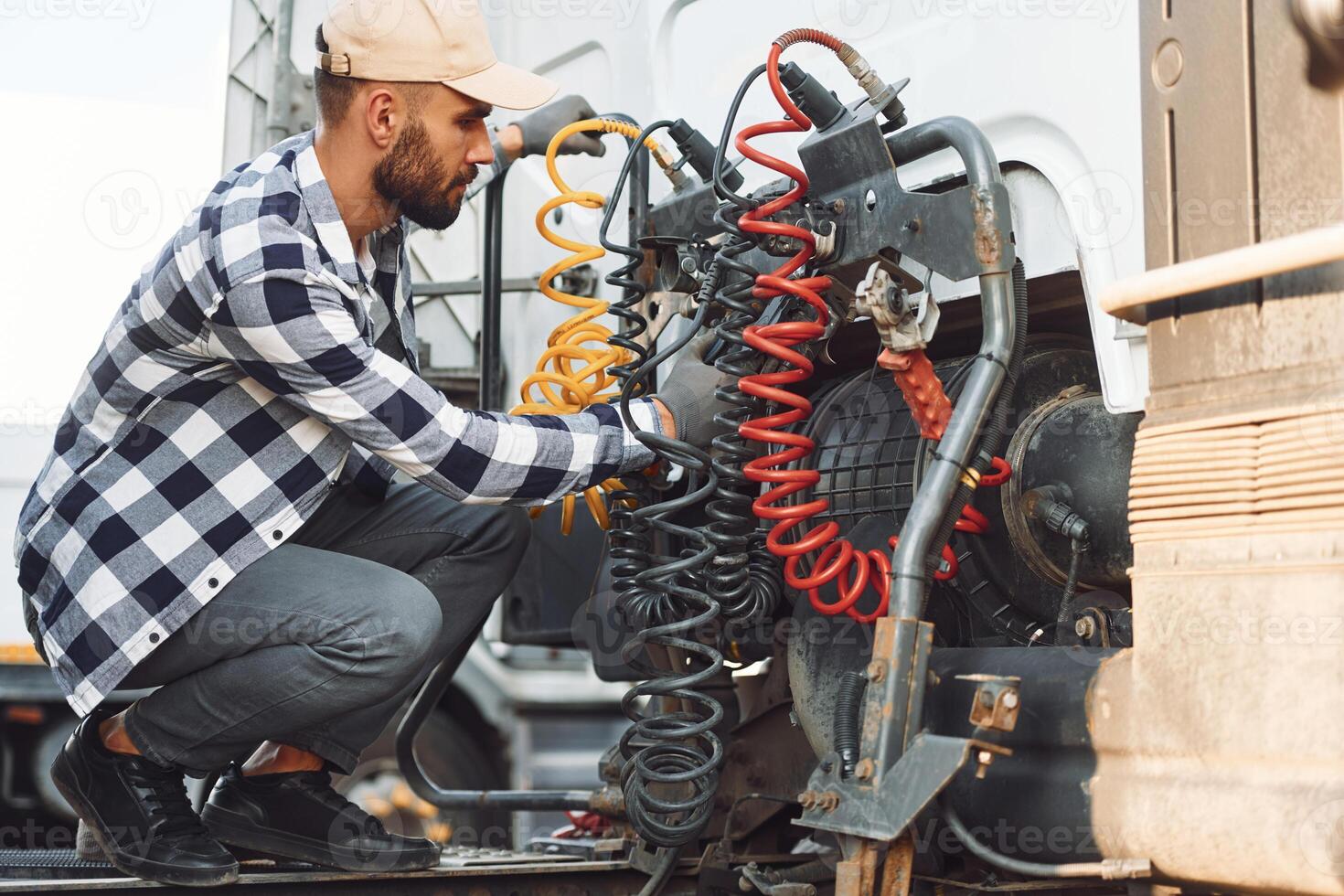 Fixing wires connection. Young truck driver is with his vehicle at daytime photo