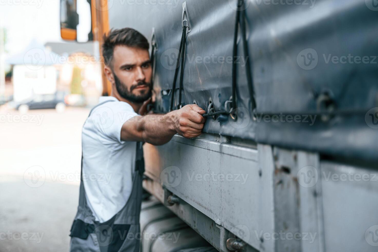 Checking the ropes. Man in unifrom doing service for big truck vehicle, photo