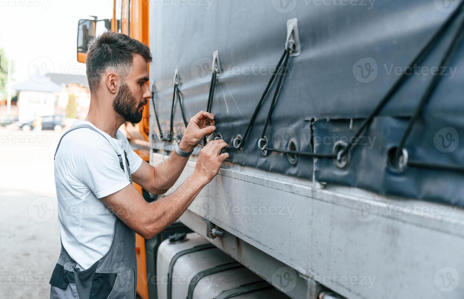 Checking the ropes. Man in unifrom doing service for big truck vehicle photo