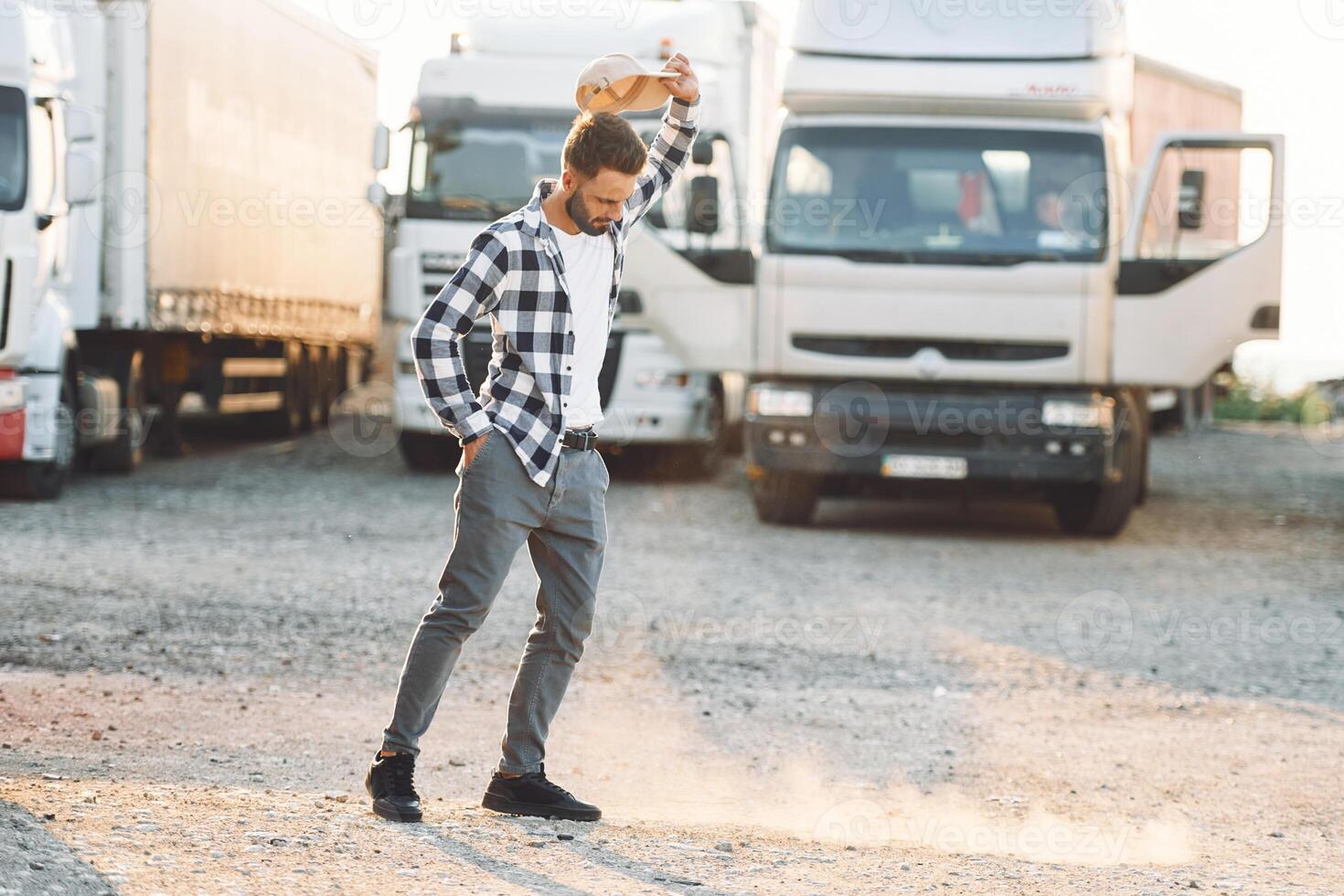 Standing ,and feeling bored. Young truck driver is with his vehicle at daytime photo