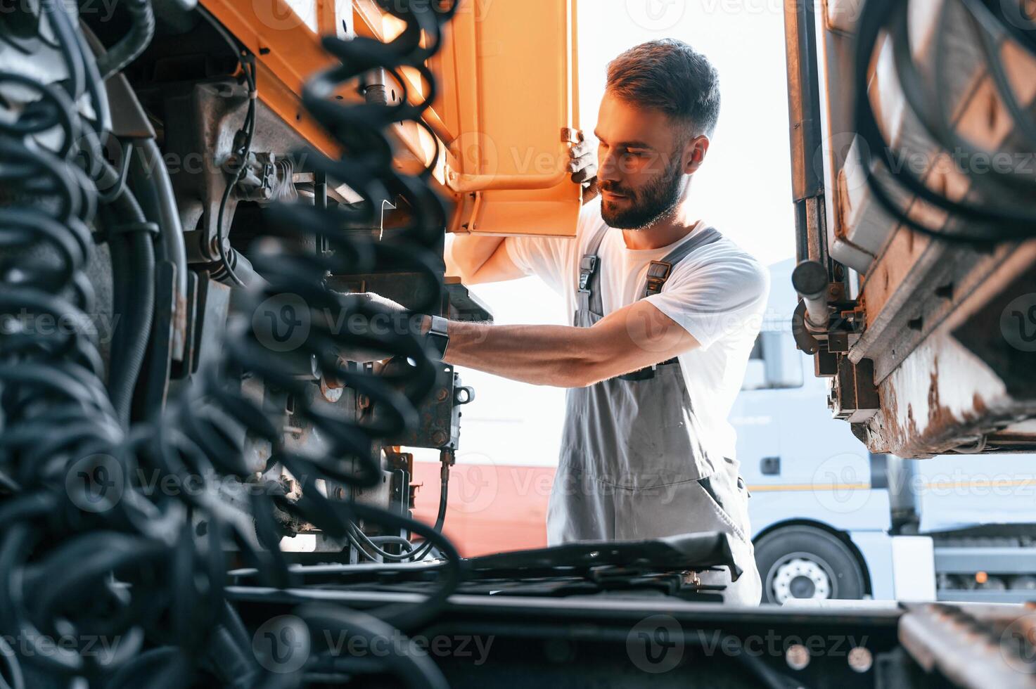 Looking at wires connection. Safety check. Man in unifrom doing service for, big truck vehicle photo